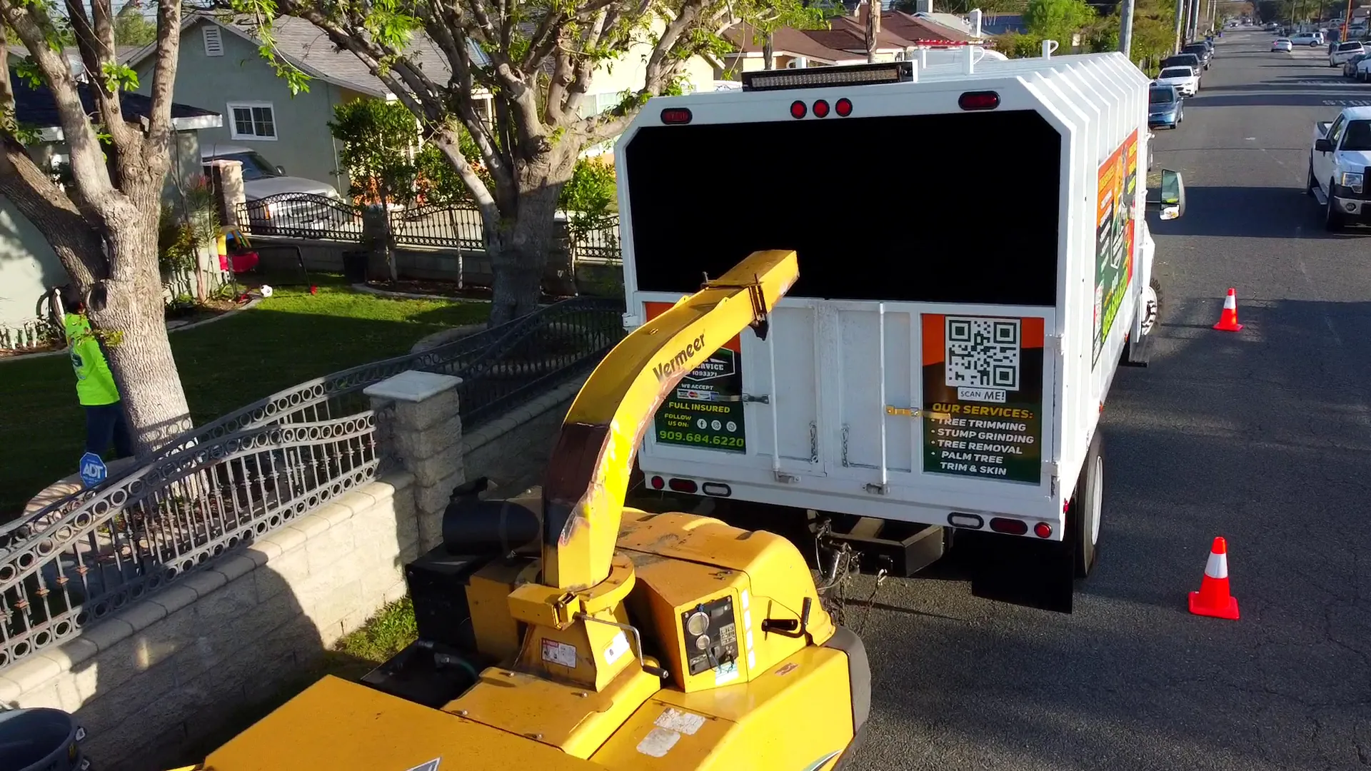 FR Tree Service chipper and truck set up with safety cones on a residential street